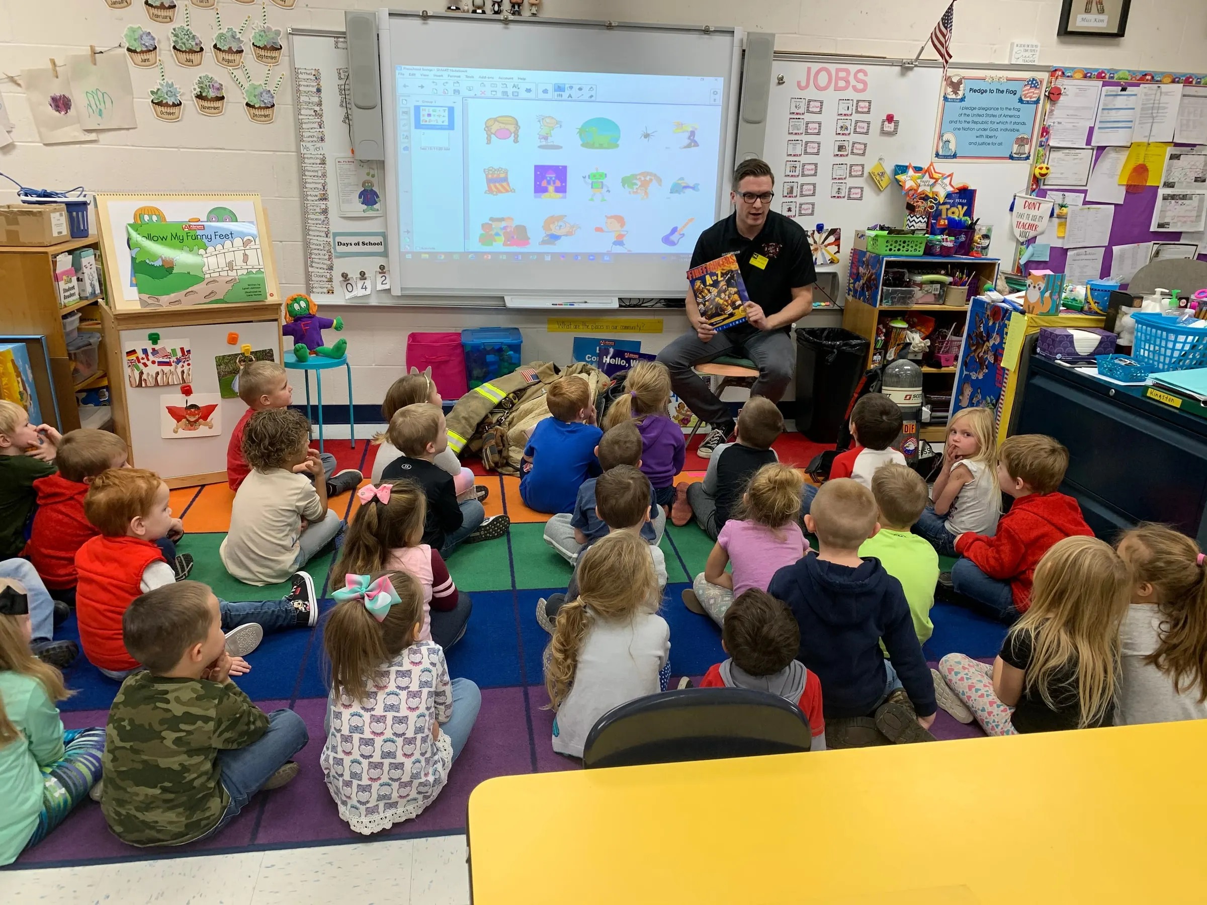 A firefighter speaking to children in a classroom during a fire safety visit.