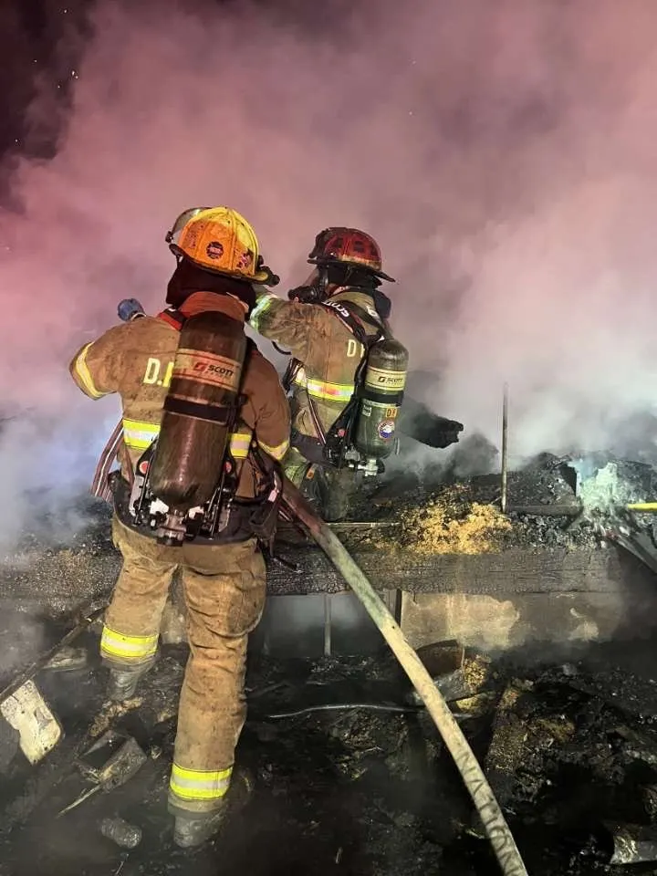 Two firefighters operating a hose line in heavy smoke.