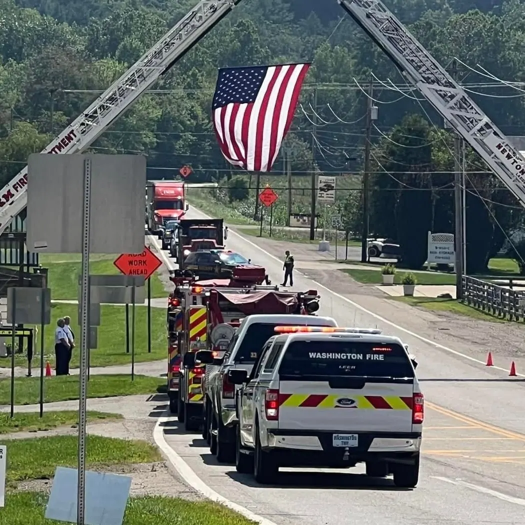 Fire apparatus staged beneath an American flag suspended over a road.