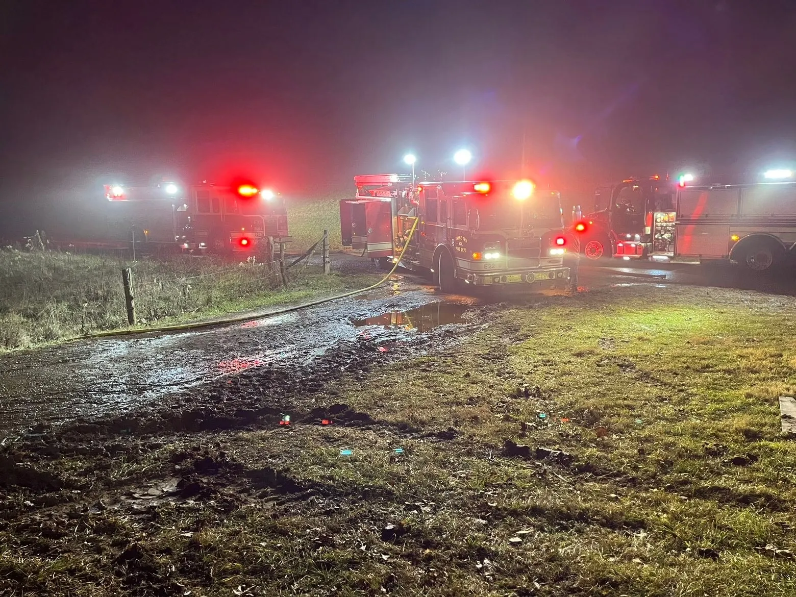 Emergency vehicles with lights operating at night on wet ground.