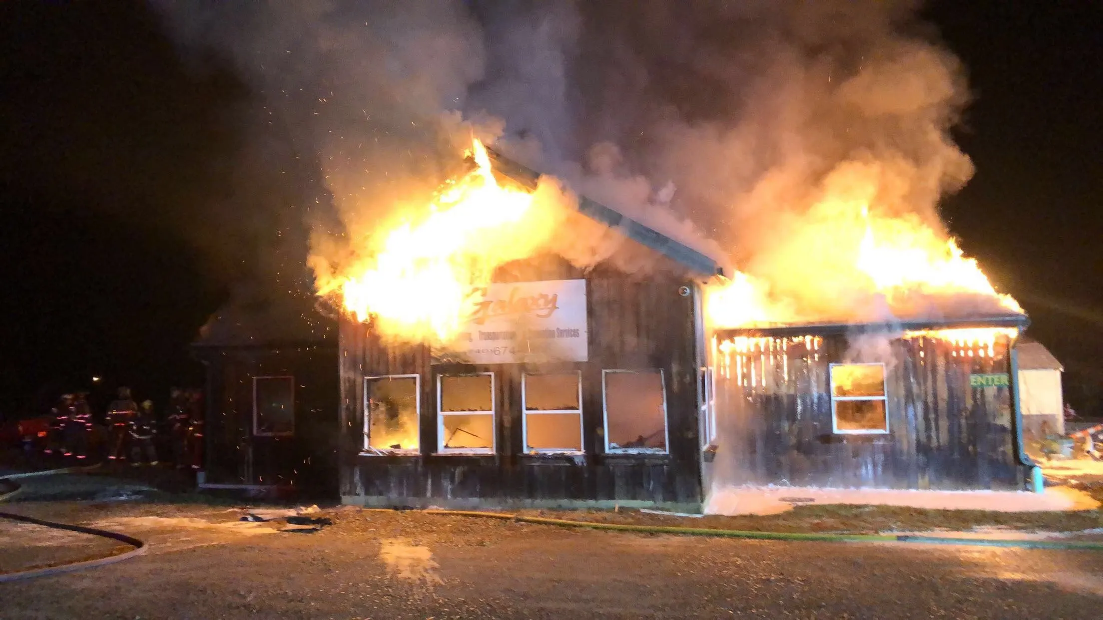 A building with flames showing through windows at night.